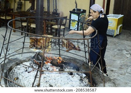 AXOS, GREECE - MAY 24: Unidentified woman prepare a barbeque on open fire place, a traditional kind of cooking in Crete, on May 24, 2014 in Axos, Greece