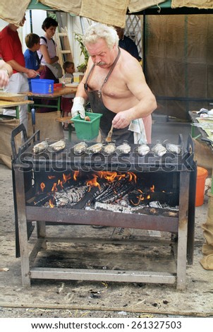EGGENBURG, AUSTRIA - SEPTEMBER 11: Unidentified cook with grilled fish on open fire by yearly festival in Lower Austria; on September 11, 2005 in Eggenburg, Austria