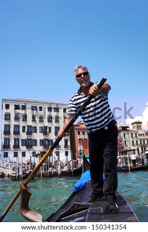 VENICE-JUNE 23: Gondolier rides gondola on the canals of Venice on June 23,2013. Gondola - is one of the symbols of Venice and major mode of touristic transport in Venice, Italy.