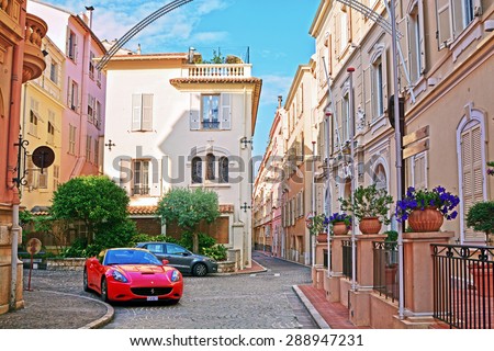 MONTE CARLO, MONACO - JUNE 2, 2015:  Red sports car Ferrari on narrow street with old colorful houses in Monaco Ville