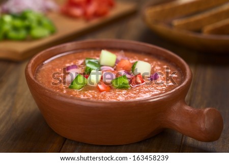 Spanish cold vegetable soup made of tomato, cucumber, bell pepper, onion, garlic and olive oil served in rustic bowl (Selective Focus, Focus on the front of the vegetables on the top of the soup)