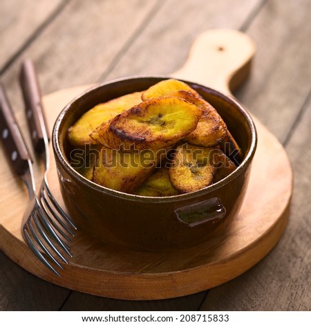 Fried slices of the ripe plantain in bowl, which can be eaten as snack or is used to accompany dishes in some South American countries (Selective Focus, Focus on the front of the upper plantain slice)