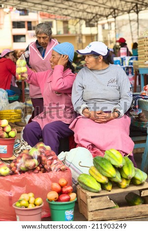 BANOS, ECUADOR - FEBRUARY 26, 2014: Unidentified female vendors offering fruits on the market on Plaza 5 de Junio on February 26, 2014 in Banos, Ecuador.