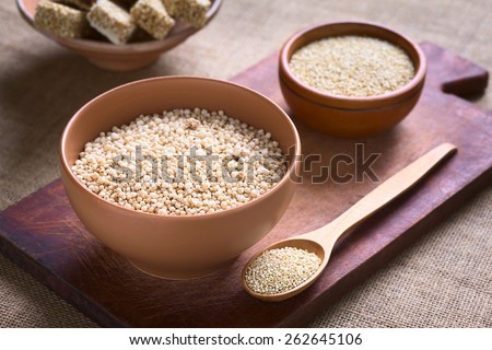 Popped white quinoa (lat. Chenopodium quinoa) cereal in bowl with raw quinoa seeds in the back photographed with natural light (Selective Focus, Focus one third into the quinoa cereal)