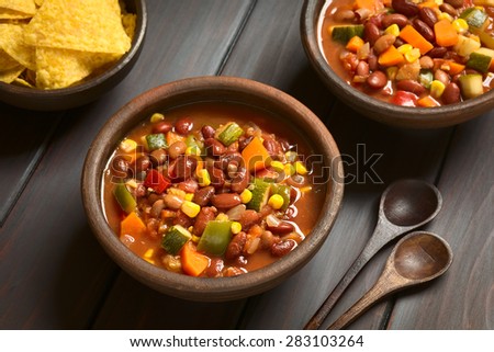Vegetarian chili dish made of kidney bean, carrot, zucchini, bell pepper, sweet corn, tomato, onion, garlic, photographed with natural light (Selective Focus, Focus in the middle of the first dish)