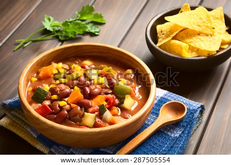 Vegetarian chili dish made of kidney bean, carrot, zucchini, bell pepper, sweet corn, tomato, onion, garlic, photographed with natural light (Selective Focus, Focus in the middle of the dish)