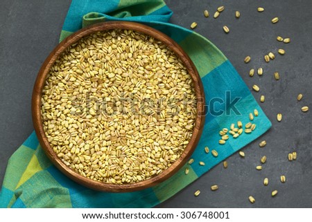 Trigo Mote boiled and husked wheat grain, commonly used in the South American cuisine, photographed overhead on slate with natural light (Selective Focus, Focus on the grains in the bowl)