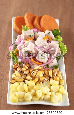 Peruvian-style ceviche out of raw dogfish (Spanish: tollo), onions and aji (Peruvian hot pepper) with corn, roasted corn and cooked sweet potato (Selective Focus, Focus on the front of the fish)