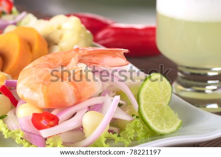 Peruvian Prawn Ceviche: King prawn on red onions and lettuce with corn, lime and sweet potato in back and the Peruvian cocktail called Pisco Sour (Selective Focus, Focus on the front of the prawn)