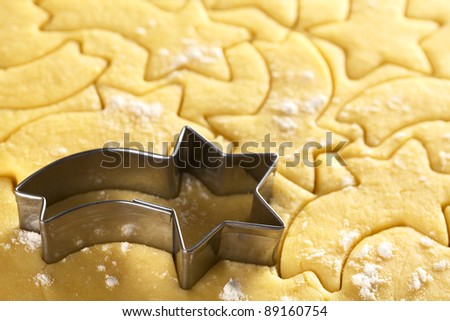 Cutting out Christmas cookies from shortcrust dough with a shooting star shaped cutter (Selective Focus, Focus on the front edge of the tail of the shooting star and the edge of the lower right arm)