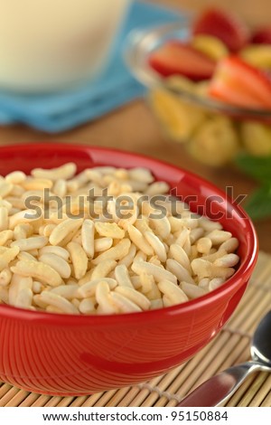 Puffed rice cereal with fruits and milk in the back (Selective Focus, Focus in the middle of the bowl)