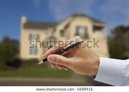 man\'s hand,holding pen,pin striped shirt,soft focus house in background