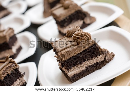 several slices of chocolate cake on white paper plates