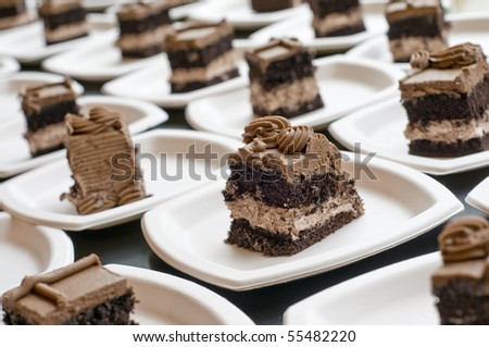 several slices of chocolate cake on white paper plates