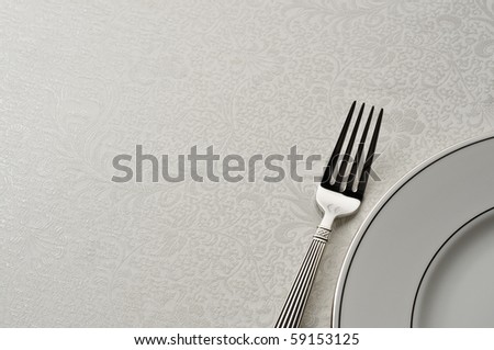 nice looking fork and plate on ornate table cloth, room for copy