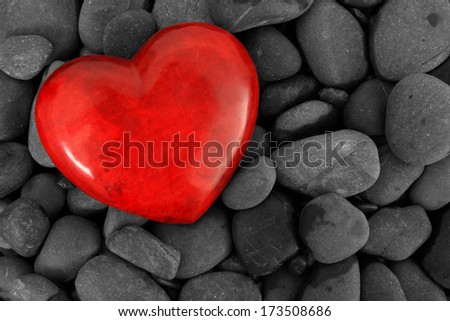 Red heart on a background of river stones.