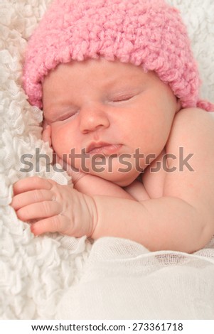 Newborn baby girl wearing a pink knitted hat.