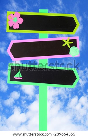 Colorful beach themed direction chalk board signs against a blue sky. Add your own text.