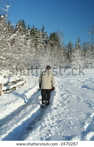 Elderly gentleman walking alone through a snow covered park.
