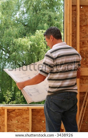 Man looking at the blue prints of his new home still under construction.