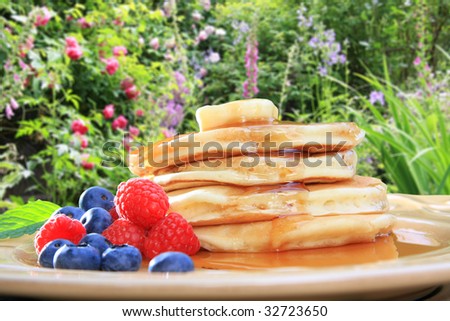 Fluffy pancakes with berries and syrup... breakfast in the garden.