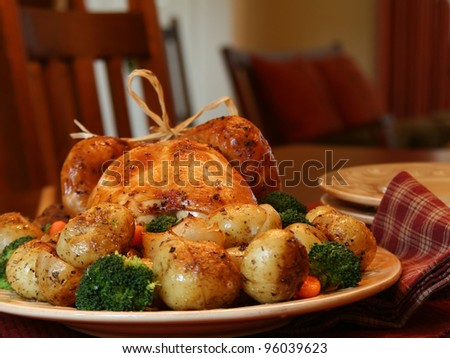 Roast chicken surrounded by roasted baby potatoes, broccoli and carrots.