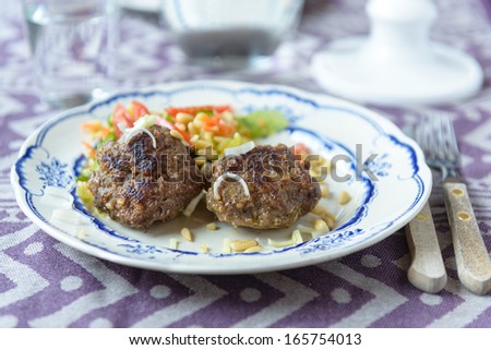 Minced beef meat ball burger patties with some salad on the side with bulgur and tomatoes
