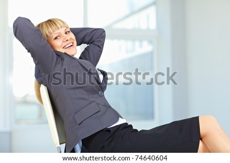 Young female executive relaxing in an office chair with hands behind head