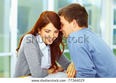 Handsome men whispering something to his girlfriend and she is listen to him and smiling