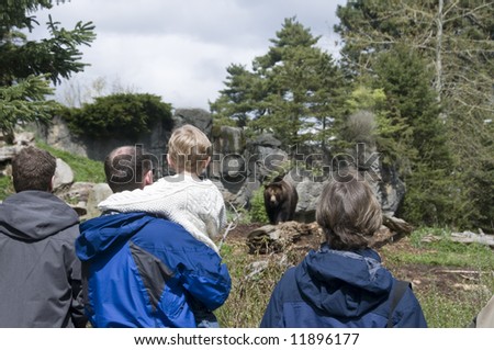 Family looking at brown bear in Zoo
