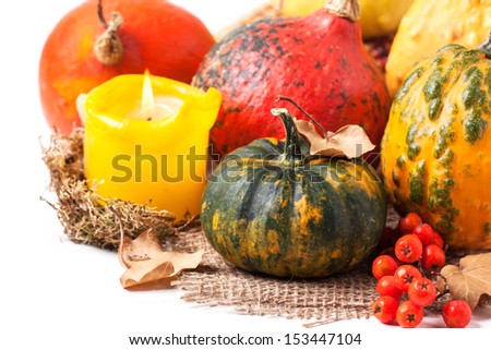 Autumn mini pumpkins and berries over white with burning candle