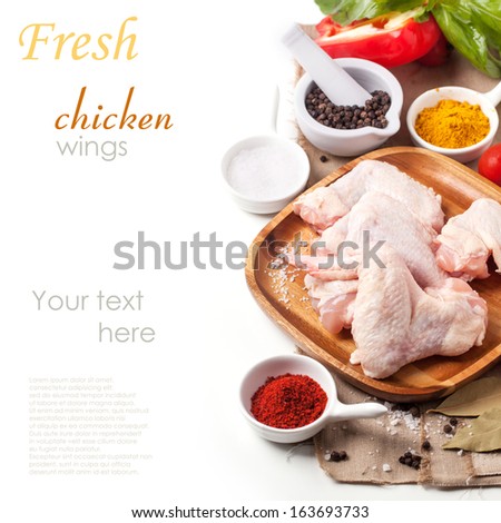 Plate of raw chicken wings with spices and vegetables over white with sample text. See series