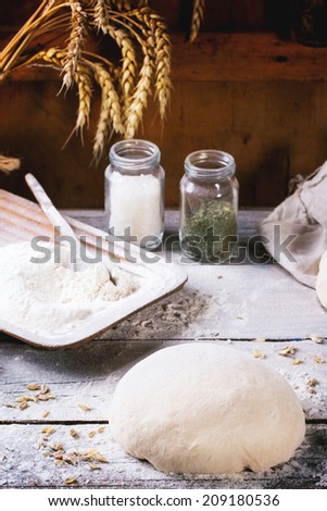 Baking bread. Dough on wooden table with flour, rolling-pin and jars with backing ingredients.