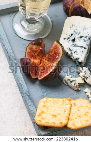 Figs with blue cheese, white wine and crackers on wooden tray. See series.