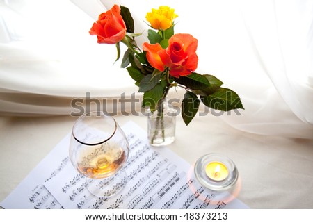 Three beautiful roses with music notes, glass and burning candle
