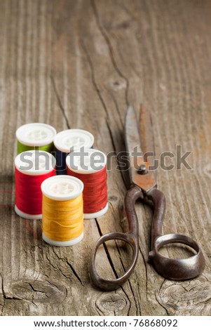 Old scissors and colorful threads on old wooden table