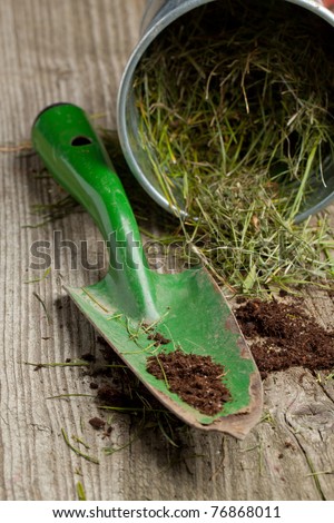 Green garden spade with ground and grass on old wooden desk
