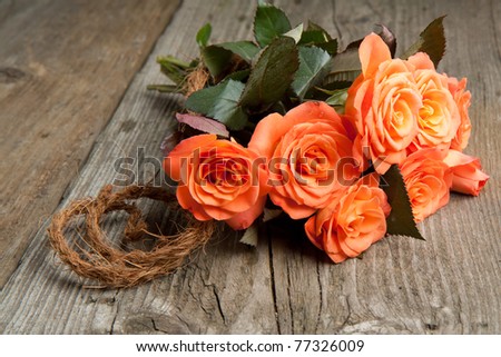 Bunch of orange roses on old wooden table
