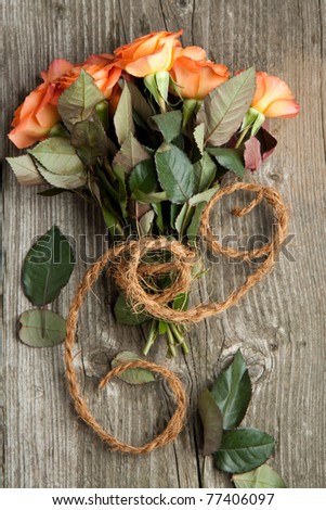 Bunch of orange roses with cord on old wooden table