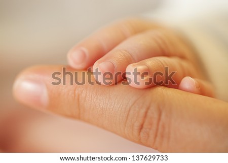 the mother holds hand of her baby