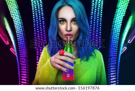 Bright girl with blue hairs is drinking cocktail.