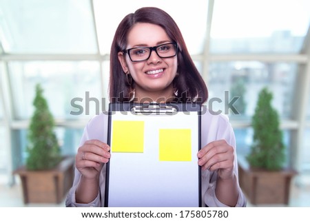 Beautiful business woman with a folder in hands. Business decisions. Office workers. Friendly smiling girl. Beautiful light background.