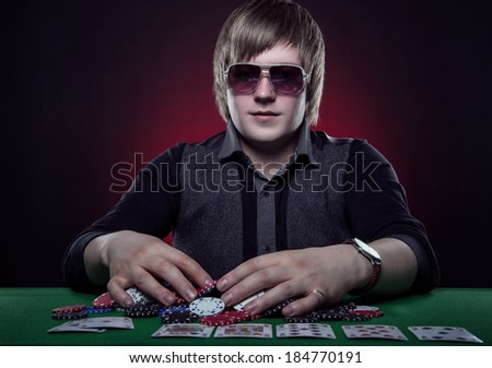 Beautiful young man on a beautiful background playing poker. Good luck in card games on the big money