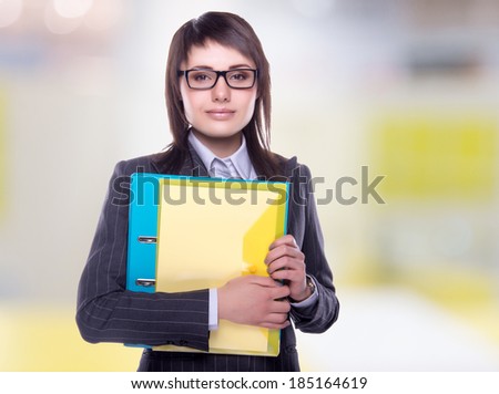 Beautiful business woman with a folder in hands. Business decisions. Office workers. Friendly smiling girl. Beautiful light background