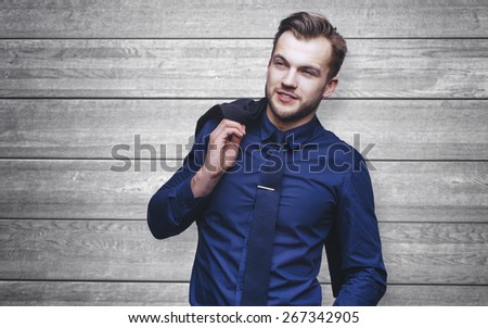 Handsome stylish young man in shirt looking at the camera. Office worker. Business decisions. Wood background