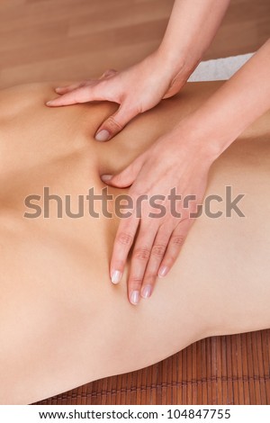 Cheerful young man getting shoulder massage at spa