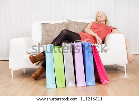 Beautiful young woman relaxing on sofa after shopping day