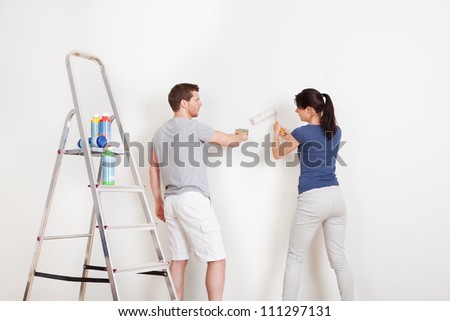 Young couple painting wall together at home