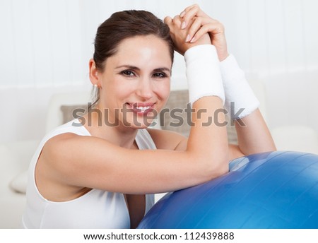 Close up of a happy smiling woman with a large blue pilates ball in a health and fitness concept