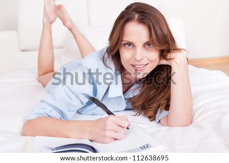 Attractive you woman lying relaxing on a sleeper couch writing in her diary